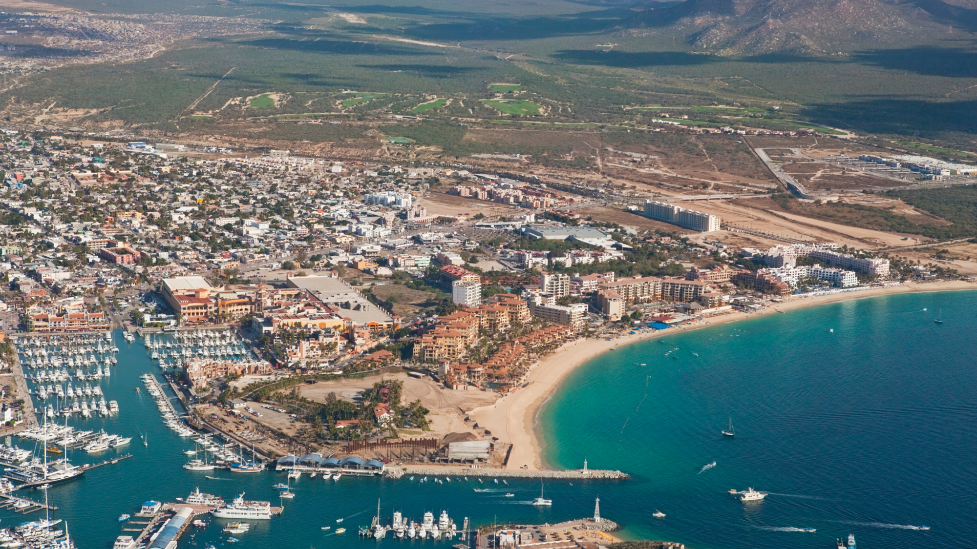 Aerial view of Cabo San Lucas, showcasing the marina, beach, and surrounding landscape