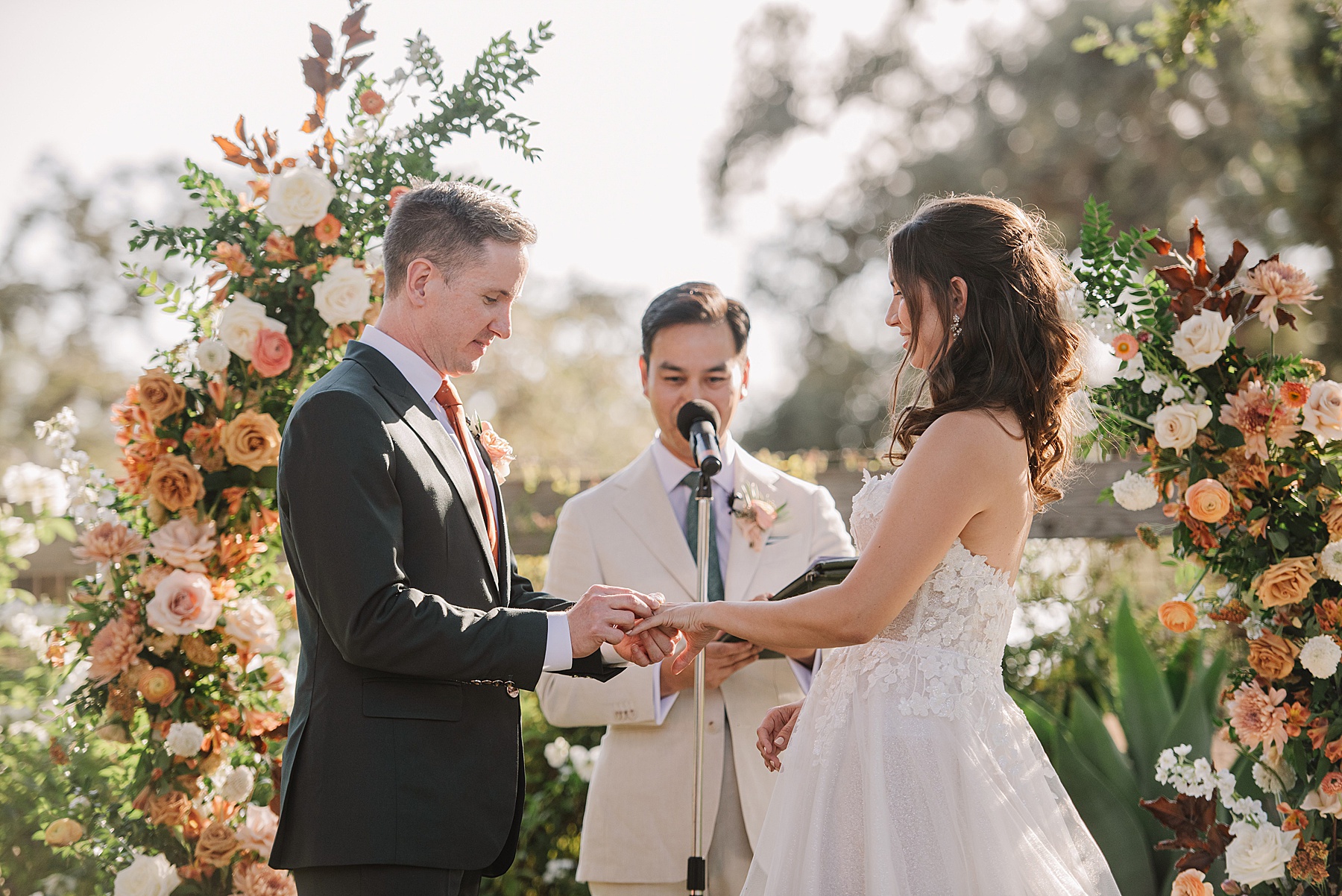 Intimate wedding ceremony at Foxen Canyon Ranch, with the couple exchanging rings in front of a stunning floral arch, surrounded by natural beauty and golden sunlight.