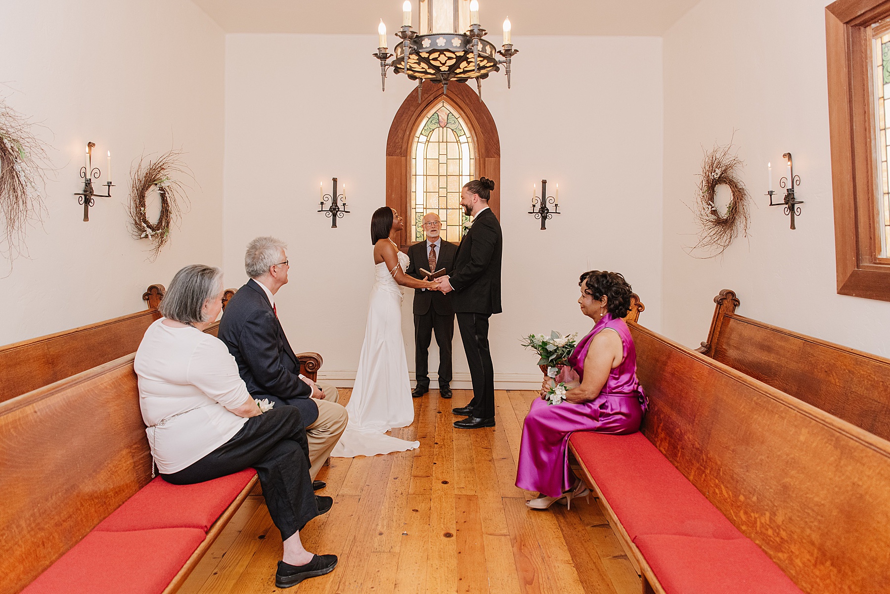 Intimate wedding ceremony at Harmony California wedding venue, featuring a cozy chapel with stained glass, natural wood pews, and elegant decor