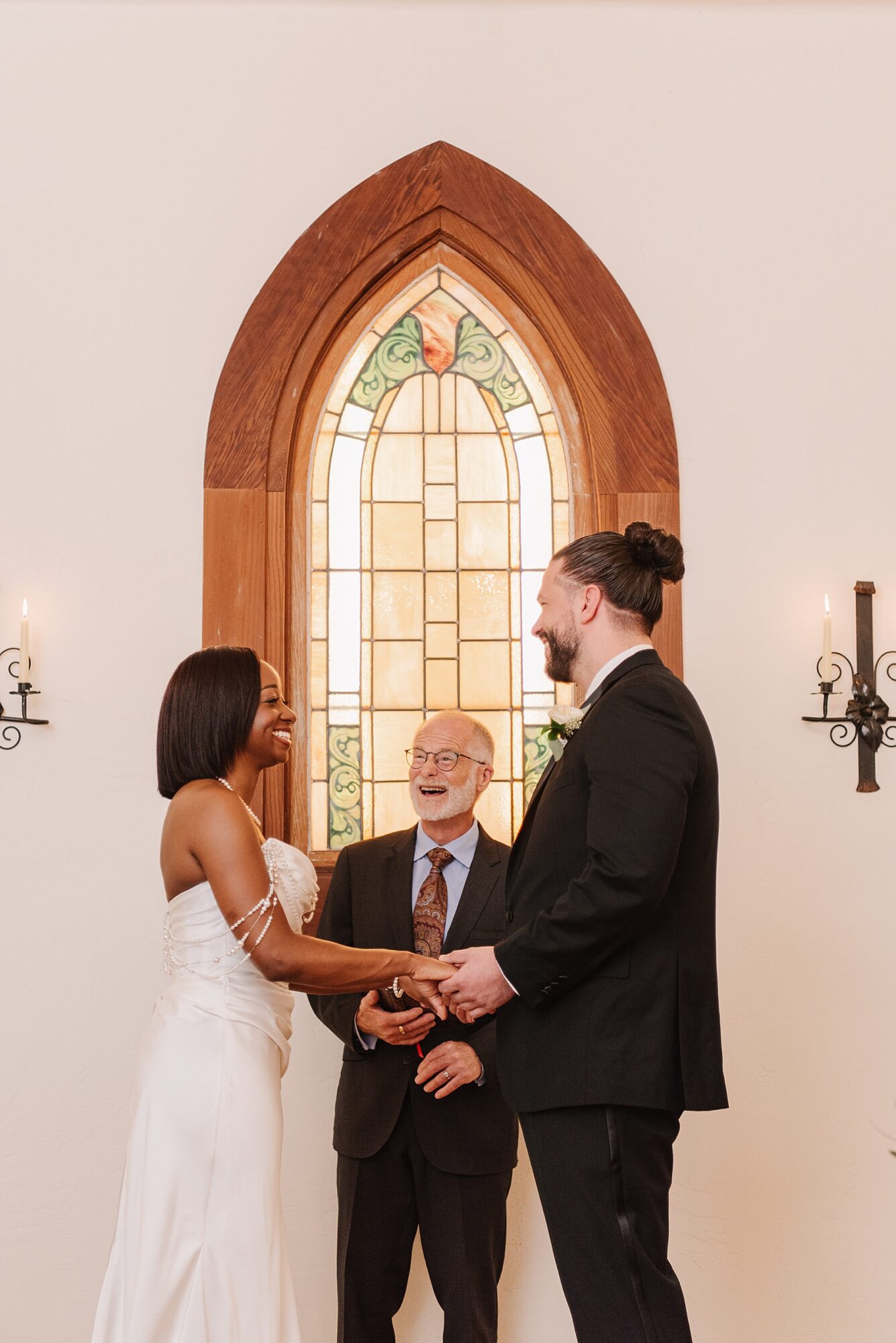 Heartfelt ceremony at Harmony California wedding venue, with the couple exchanging vows in front of a stunning stained glass window, surrounded by warmth and joy.