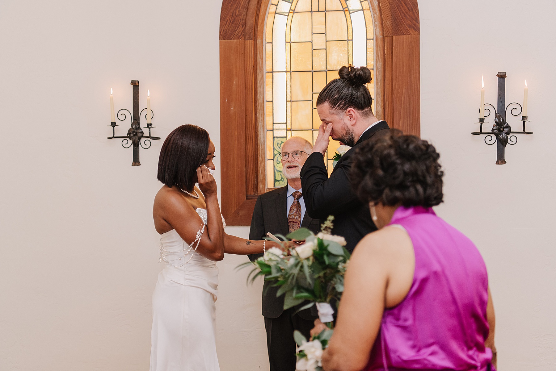 Heartfelt ceremony at Harmony California wedding venue, with the couple exchanging vows in front of a stunning stained glass window, surrounded by warmth and joy.