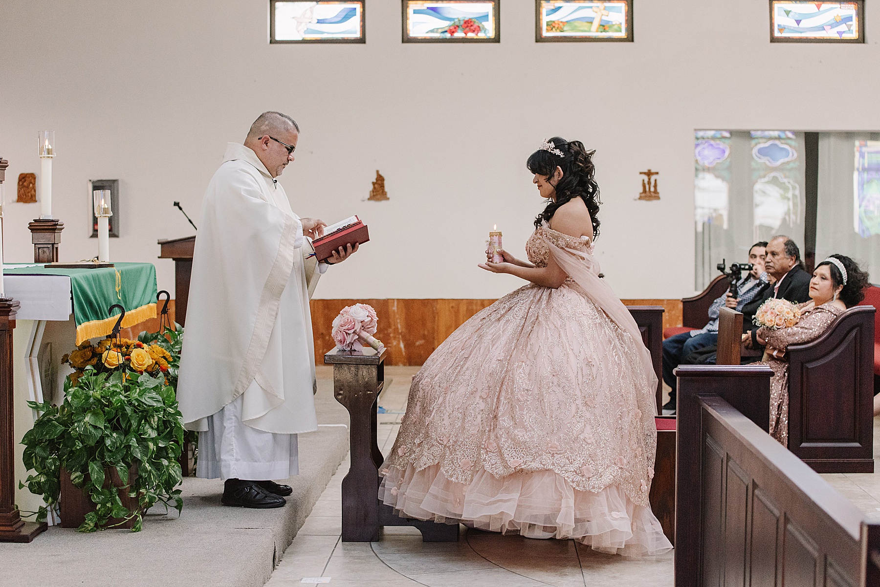 Mary Luz presents a candle during her church ceremony, a meaningful part of her Tooth + Nail Winery Quinceañera celebration, while wearing a stunning blush ballgown.