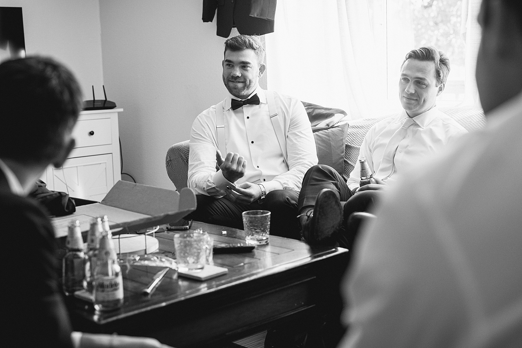 Groom and groomsmen relaxing with drinks and conversation on the wedding morning, embodying calming wedding morning tips for a stress-free start.