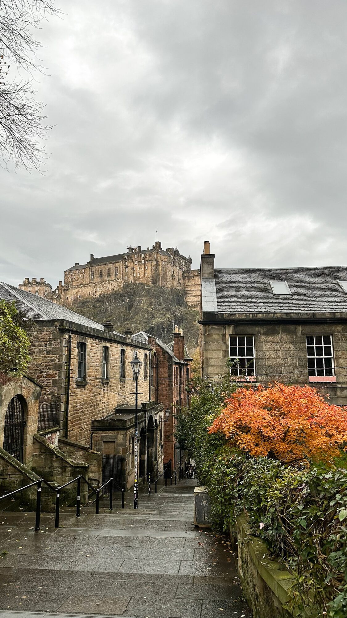 Exploring Scotland with a view of Edinburgh Castle rising above old stone buildings and autumn trees in the foreground.
