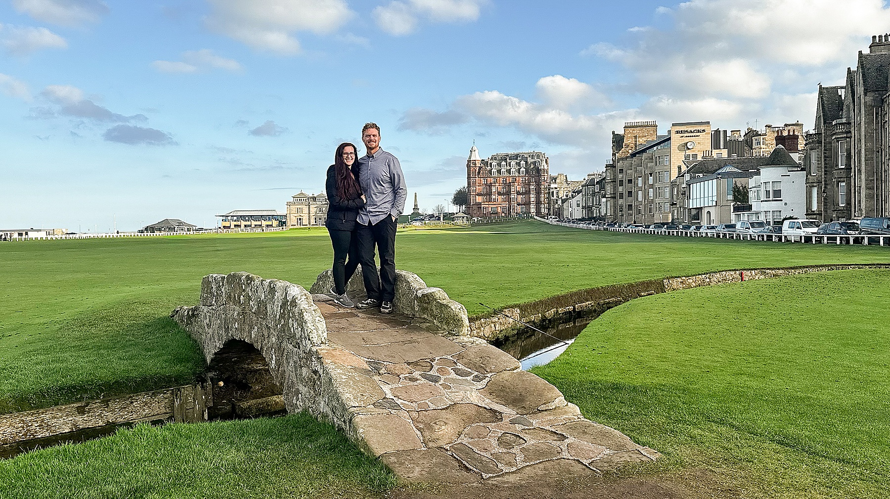 Exploring Scotland with a couple standing in Glencoe surrounded by dramatic mountains, rocky trails, and misty skies.