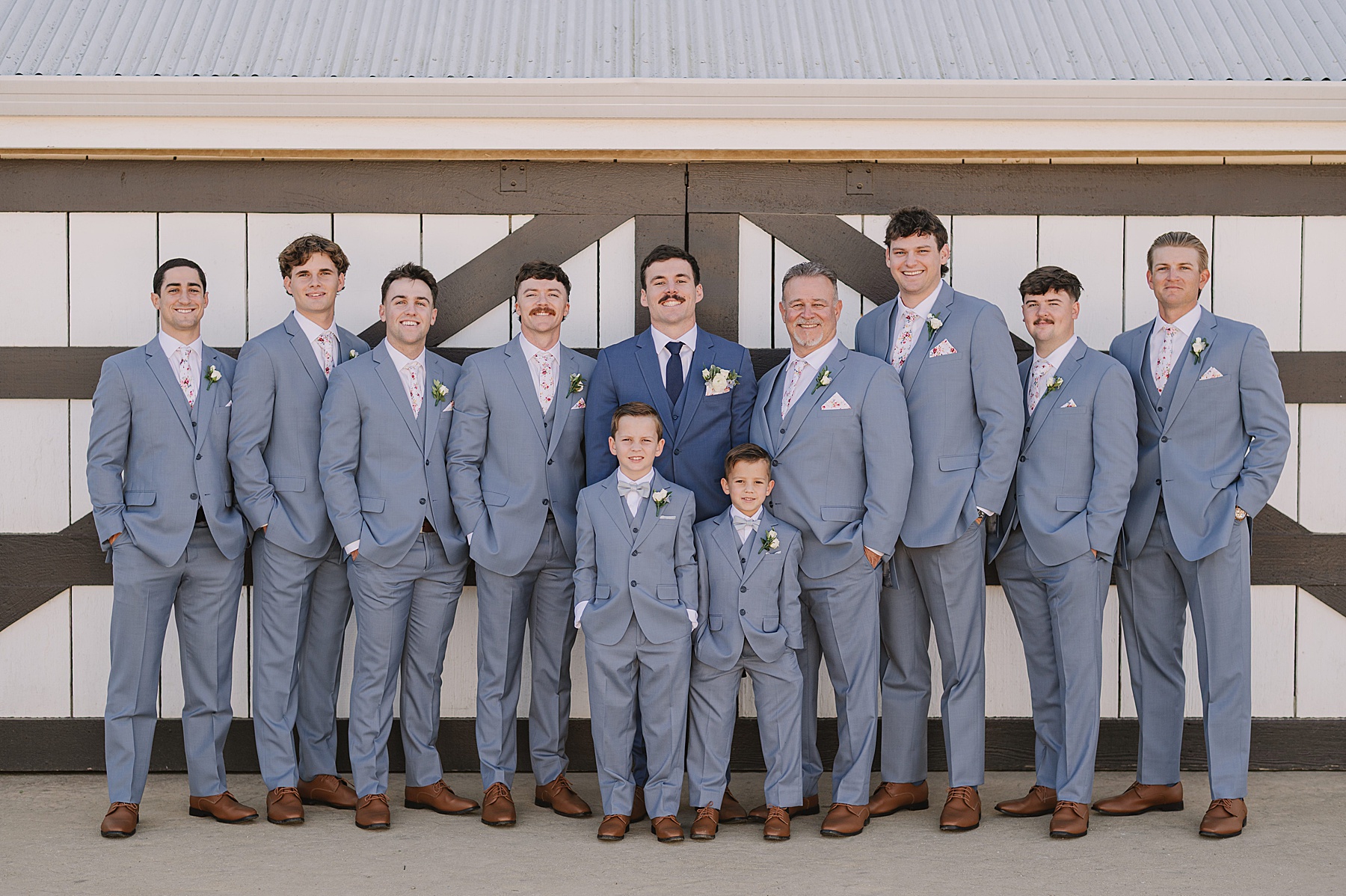 Groom and groomsmen portraits at White Barn Wedding Venue in Edna Valley, California featuring coordinated blue suits and the venue’s iconic white barn backdrop.