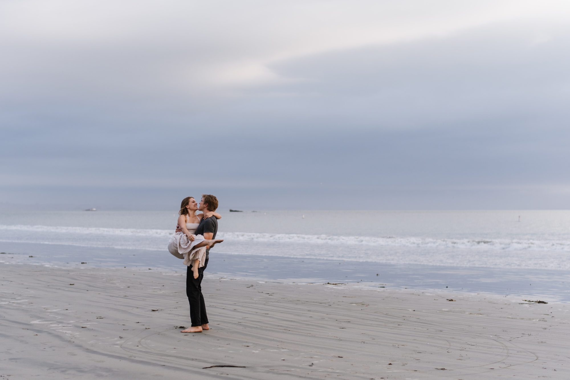 Man holding woman on beach in San Luis Obispo