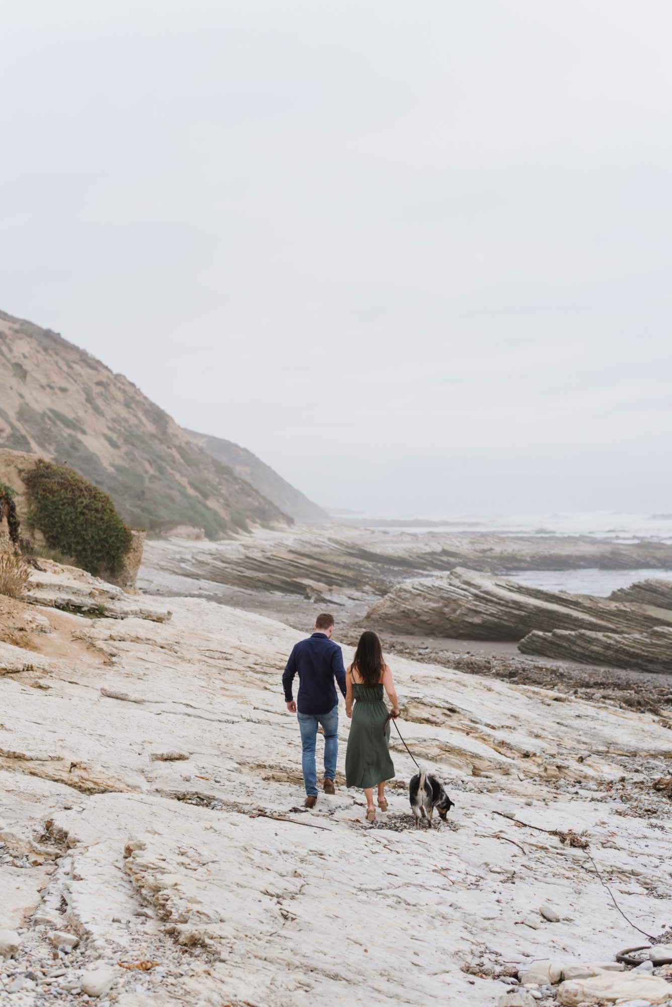 Man and Woman walking their dog on the beach for their engagement photos